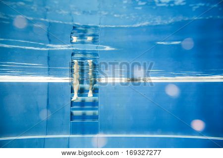 a young man and woman are testing the water temperature in a pool with their hands and feet