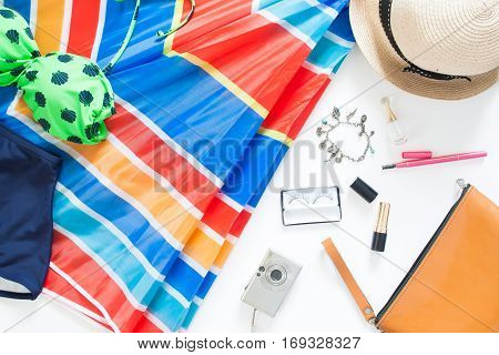 Flat lay of summer fashion with green color swimsuit colorful beach umbella and girl accessories on white background