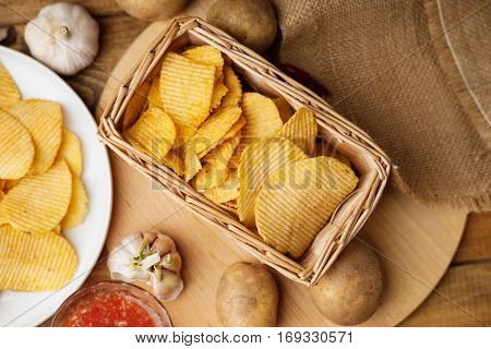 Crispy potato chips in a wicker basket, potato, gralic and sauce