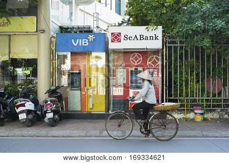 Hanoi, Vietnam - Sep 14, 2014: Unidentified woman cycles passing ATM on Le Dai Hanh street