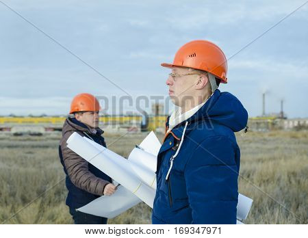 Engineers at a construction site with drawings in hand