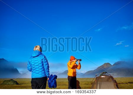 man hiker photographer taking picture on the mountain lake background in Iceland