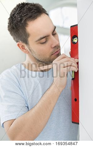 Mid-adult man marking on wall with level