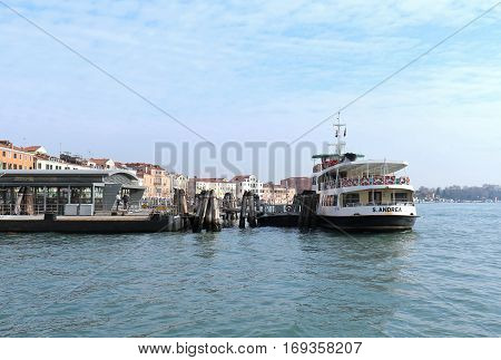 VENICE ITALY - JANUARY 09; One of public boat transport Vaporetto stops with people waiting to board in Venice Italy - January 09 2017: Vaporetto is water bus network with 19 scheduled lines that serve locals and tourists within Venice.