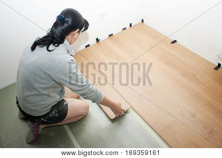 young beautiful woman puting laminate flooring indoor