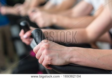 Young man and woman biking in the gym exercising legs doing cardio workout cycling bikes.