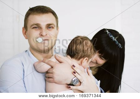 happy family consisting of mom and dad's baby boy. happy family relationships. mother entertains a child, his father holding him in her arms. his father in the mouth empty.