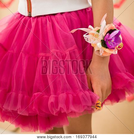 Closeup of beautiful flower decoration for wrist. Girl in fluffy skirt and nice braslet. Fashion and accessories