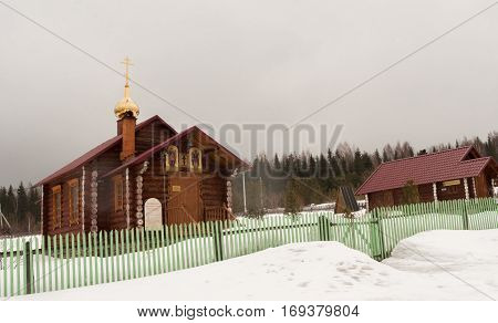 Verkhniy Tagil, Russia - 11.07.2016: Small wooden Church stands in the snow near the forest.