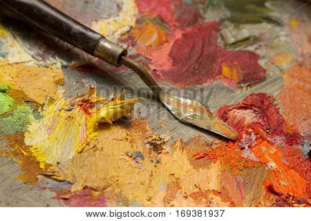 spatula on a palette with oil paints. yellow paint extruded from the tube