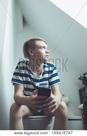 Boy Using Smartphone In Bathroom