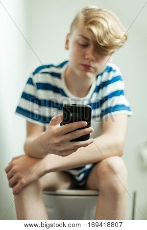 Teen Using Smartphone On Toilet
