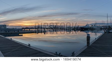 First rays of sun peeking over the horizon. Port twilight in the Valencia harbor cranes working loading transport ships, red and blue skyline reflected in water. gigapan
