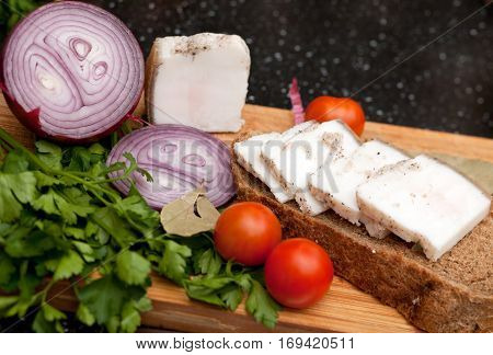 Lard on bread tomatoes onions and fresh herbs on the table