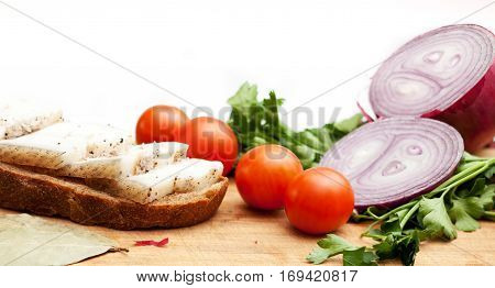 Lard on bread tomatoes onions fresh and herbs on a white background