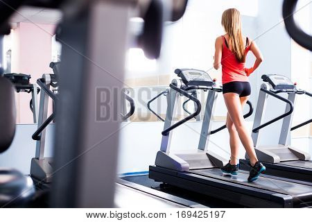 Active young woman running on treadmill at the gym exercising. Run on a machine.