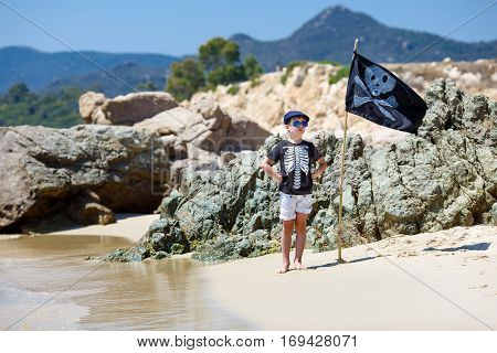 Cute boy dressed as pirate on tropical beach during summer holiday vacation