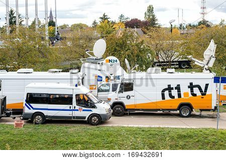 STRASBOURG FRANCE - OCT 7 2015: Tv Television Trucks with multiple Satellite parabolic antennas and fiber optic cables going inside reporting live the official French president visit to the European PArliament in Strasbourg France