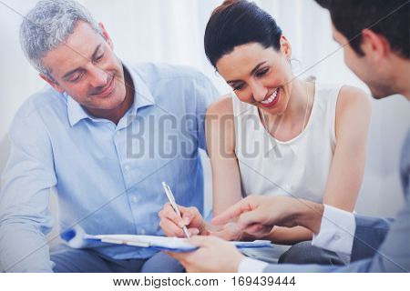 Smiling woman sign on a contrat with her partnership on sofa at office