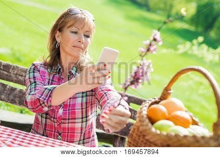 Beautiful mature woman in the park using a smart phone.