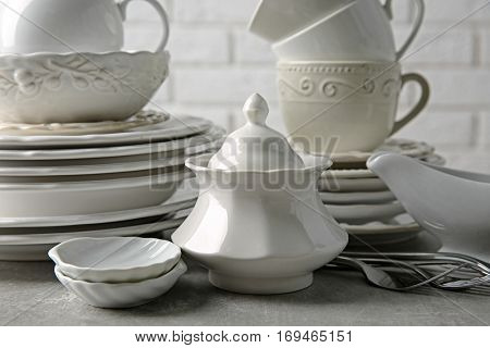 Porcelain dishware on table and white brick wall background