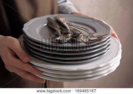 Female hands holding pile of dishware, closeup
