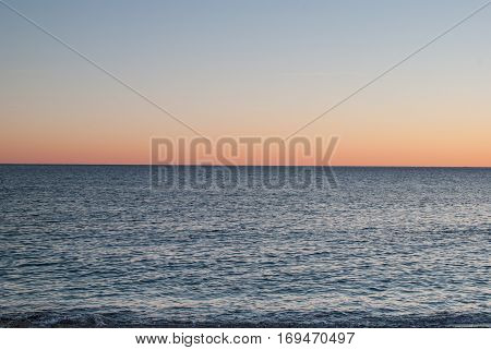 Open sea at sunset with colorful gradient sky background, horizon line splitting the photo in half