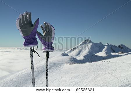 Ski gloves on ski poles on the background of southern slope Aibga Ridge of the Western Caucasus at Rosa Khutor Alpine Resort