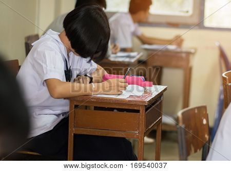 students writing test exam on paper for Admissions in high school with uniform student in School classroom of Thailand exam student background and education concept