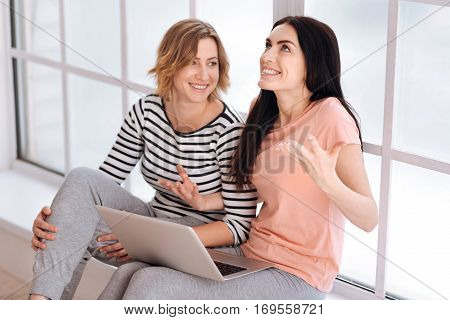 Can you believe that. Cheerful artistic brunette girl telling her friend an exciting story while showing her feelings using her gestures and face