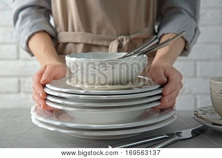 Female hands holding pile of porcelain dishware, closeup