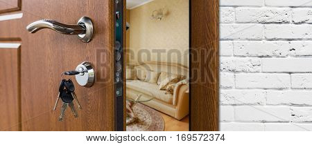 Half opened door handle closeup, entrance to a living room. Welcome, privacy concept. Door lock with keys, white brick wall, modern interior design.