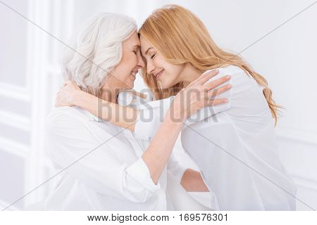 My dear. Delighetd loving adult woman and her mother embracing and expressing love while resting together at home