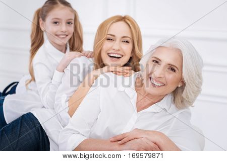 Warm atmosphere. Cheerful content smiling amily members having fun and resting at home while sitting on the white couch
