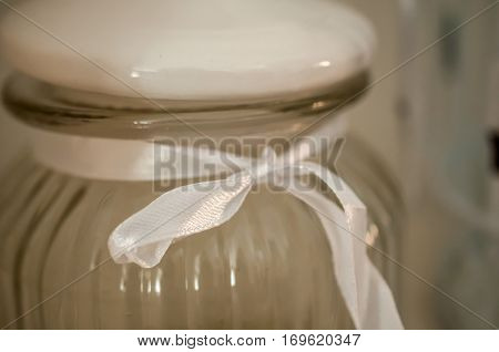 A glass can with decorative white ribbon and a bow