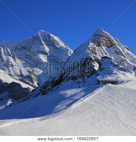 View from the Mannlichen ski area Grindelwald. Snow covered mountains Monch and Lauberhorn. Chair lift and ski slope.