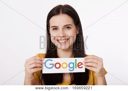 Kiev, Ukraine - August 22, 2016: Woman hands holding colorful Google logotype printed on paper on grey background.Google is USA multinational corporation.