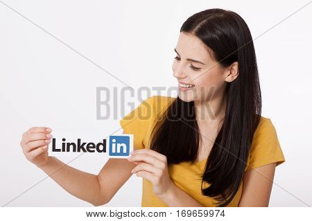 KIEV, UKRAINE - August 22, 2016: Woman hands holding Linkedin logo sign printed on paper on white background. Linkedin is a business social networking service.