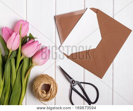 Pink Tulips And Envelope With Blank Papr On The White Wooden Table,