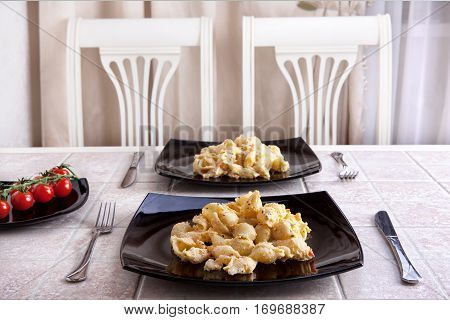 tasty pasta for two large black plate on the dining table.