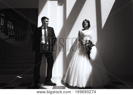 portrait of beautiful bride and stylish groom. Woman in wedding white dress and man in black suit. concept of happy marriage and strong family. black-and-white geometry and shadows