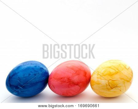 Three painted Easter eggs: blue, red and yellow.