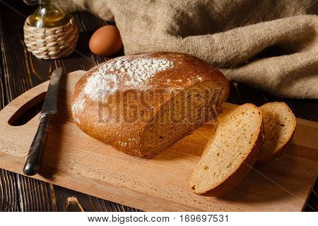 Rye bread lies on a breadboard two pieces of bread nearby