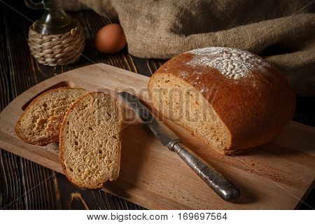 Rye bread lies on a breadboard two pieces of bread nearby