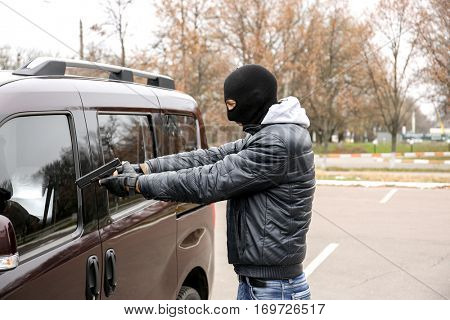 Male thief with pistol trying to steal car
