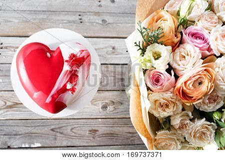 Red heart cacke desserts and bouquet of flowers on wooden background. dessert for breakfast on Valentine's Day.