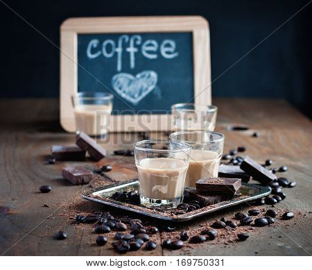Shot glasses with homemade baileys roasted coffee beans and chocolate chalk board heart drawing love selective focus toned image