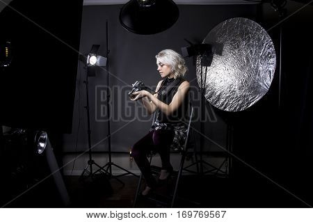 Creative female professional photographer in a strobe lighting studio. She portrays an independent self employed freelance entrepreneur. The image depicts the photography arts.