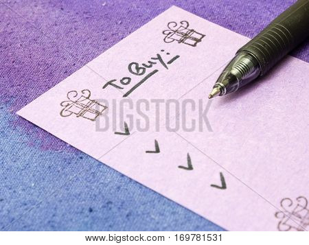 To buy list for holidays with pen on purple background