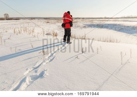 photographer takes winter landscape at dawn in the bitter cold.